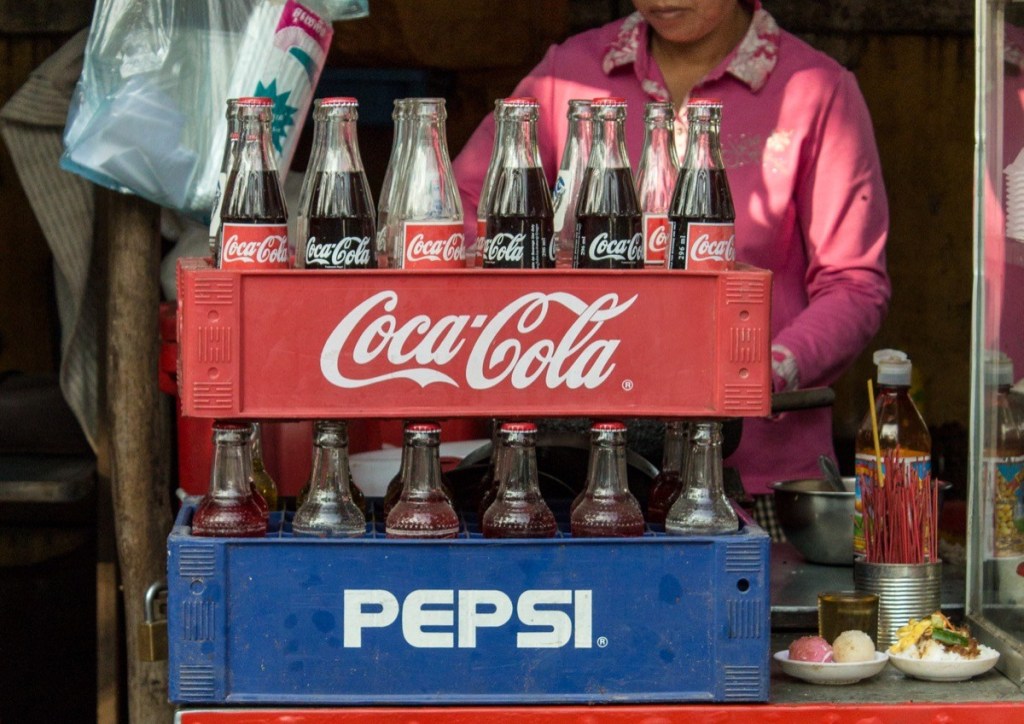 Phnom Penh, Cambodia- January 02, 2014. Coca-Cola and Pepsi bottles stacked in plastic container - vintage style. Symbolic representation of one of the greatest business rivalries of all time. - Image